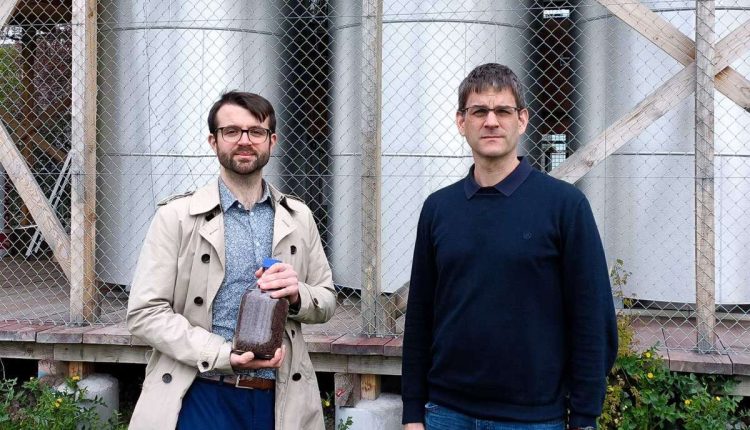 ETH-Forschenden Samuel Heiniger (links, mit einem Glas Eisenerz) und Professor Wendelin Stark vor den drei Eisenreaktoren am Campus Hönggerberg der ETH Zürich